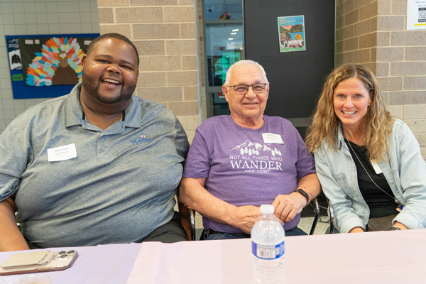 three people smile for the camera
