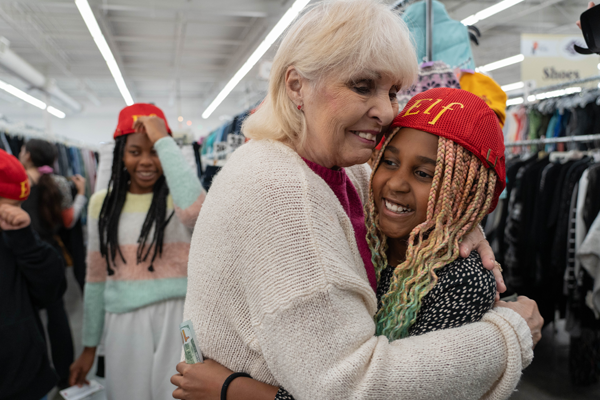 girl wearing an elf hat hugs woman in a store