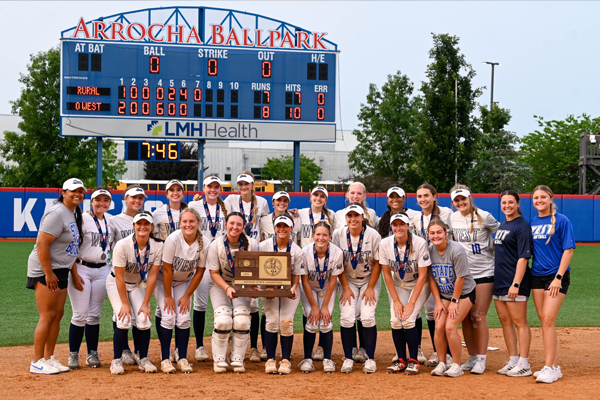 softball team holds trophy on the field